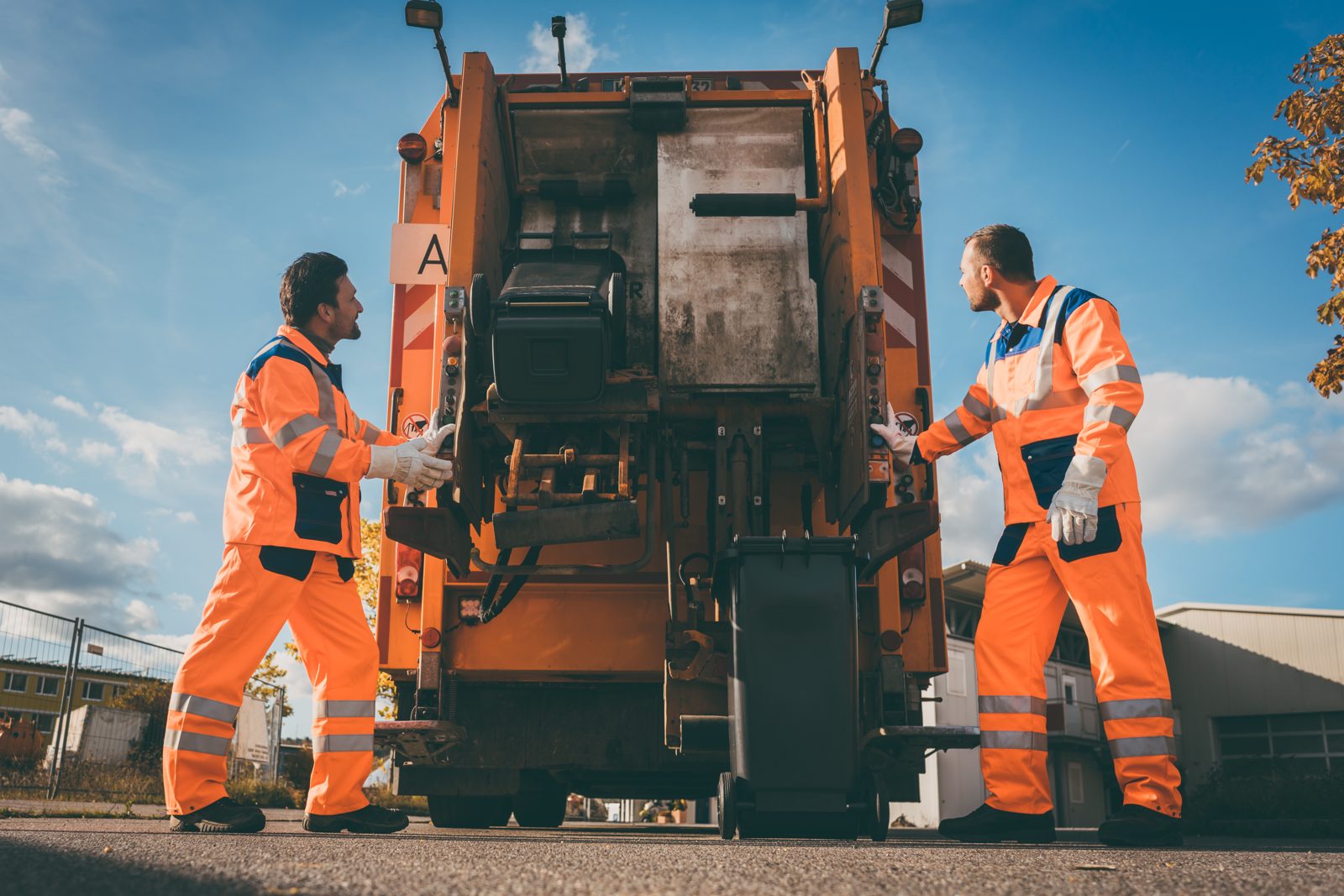 Refuse collection workers loading garbage into a waste truck